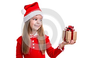 Happy christmas girl holding and lookning at the gift it in the left hand, wearing a santa hat isolated over a white