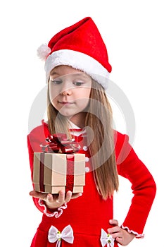 Happy christmas girl looking at the gift holding it in the hand, wearing a santa hat isolated over a white background
