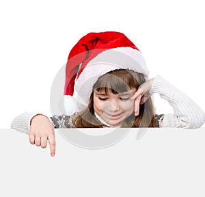 Happy Christmas girl with santa hat looks out from behind a white banner and points down. isolated on white background