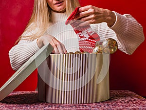 Happy Christmas. Preparing Christmas presents. Woman puts red socks with patterns in a large striped gift box