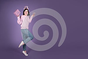 Happy Christmas woman with gift and Xmas decorations on purple banner background with copy space