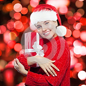 Happy Christmas woman in Santa hat having fun with red gift box
