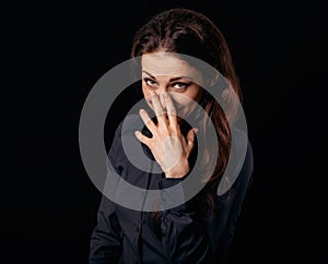 Happy chuckling fun business beautiful woman covering the mouth the hand on blue shirt on black background with empty copy space.