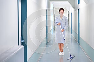 Happy cleaner mopping floor in hospital