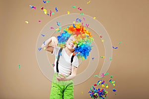 Happy clown boy with large colorful wig. Let`s party! Funny kid