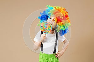 Happy clown boy in large colorful wig. Let`s party! Funny kid cl