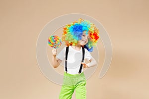 Happy clown boy in large colorful wig. Let`s party! Funny kid cl