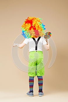 Happy clown boy in large colorful wig. Let`s party! Funny kid cl