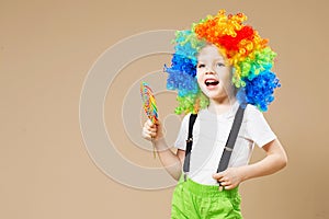 Happy clown boy in large colorful wig. Let`s party! Funny kid cl