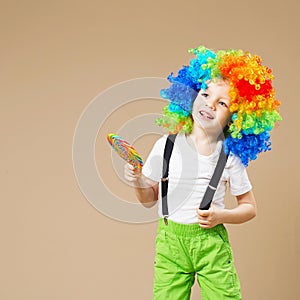 Happy clown boy in large colorful wig. Let`s party! Funny kid cl