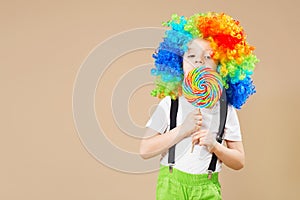 Happy clown boy in large colorful wig. Let`s party! Funny kid cl