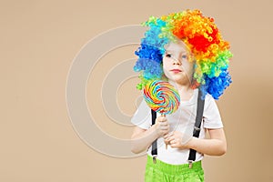 Happy clown boy in large colorful wig. Let`s party! Funny kid cl