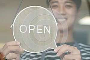 Happy Coffee Shop owner in an apron turning open sign board on glass door. Small business owner opening a small business