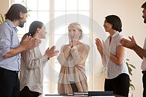 Happy colleagues clap hands greeting businesswoman with success