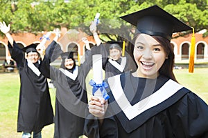 Happy college graduate holding a diploma with friends photo