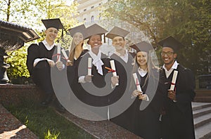Happy college graduates standing in row with diplomas