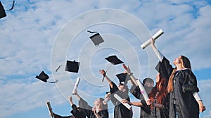 Happy college graduates tossing their caps up at sunset.