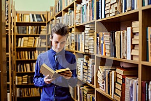 Happy college student in the library fascinated by reading an interesting book