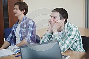 Happy college students talking in class