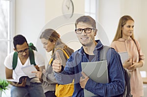 Happy college or university student who has achieved success in studies shows a thumbs up