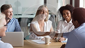 Happy caucasian manager and african client handshaking at group meeting