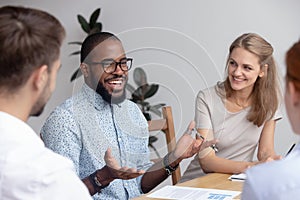 Happy confident african male business coach leading diverse team meeting