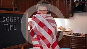 Happy confident boy wrapping in American flag looking at camera laughing. Live camera zoom in to satisfied self-assured