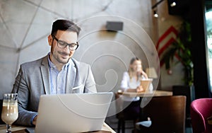 Happy confident businessman working, using laptop in office