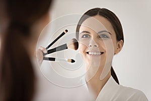 Happy confident girl putting makeup on beautiful face