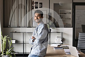 Happy confident handsome young Indian business man posing in office