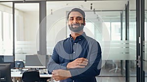 Happy confident Indian businessman standing in office, portrait.