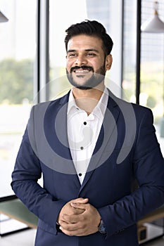 Happy confident Indian company CEO man standing in office