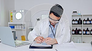 Happy, confident male scientist satisfied with science test results. Young intern writing and working on a computer with