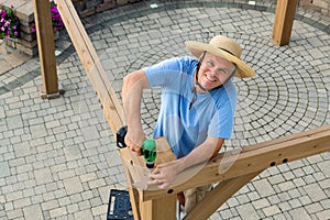 Happy confident man erecting a new outdoor gazebo