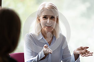 Happy confident mature businesswoman speaking, negotiating on deal at meeting