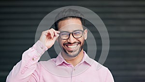 Happy, confident and relaxed young nerd man wearing glasses and smiling while looking into the camera. Portrait of