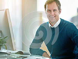 Happy, confident and smiling businessman sitting at his desk and feeling satisfied with his career and job choice