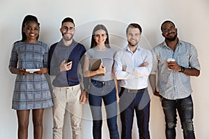 Happy confident successful multiethnic workers standing near wall.