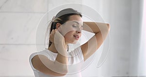 Happy confident young beautiful woman doing hair looking in mirror