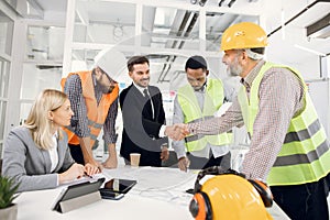 Happy construction team shaking hands during conference