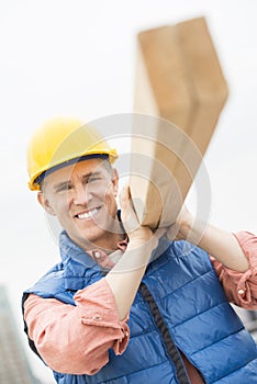 Happy Construction Worker Carrying Wooden Plank