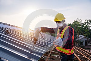 Happy construction worker safety wear using electric drill tools install on new roof metal sheet, Roof construction concept