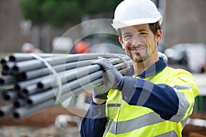 happy construction worker on site holding pipe
