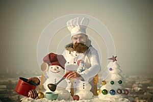 Happy cook, snowmen and snow xmas tree on blue sky