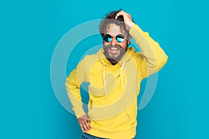 Happy cool guy with curly hair and moustache holding hand on head