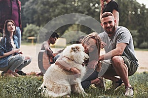 Happy cople with dog. Group of people have picnic on the beach. Friends have fun at weekend time