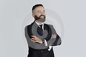 Happy corporate employee in business suit and tie crossing his arms on light grey background. Leadership and management