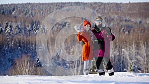 Happy coulple waving hands to camera in mountain ski resort at sunny day. Winter, sport, holidays, relationship, love