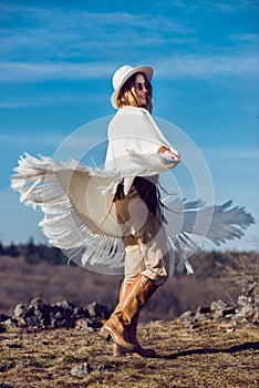 Happy country woman enjoying nature in mountains wearing poncho