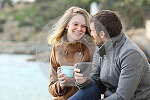 Happy couple of adults talking in winter on the beach